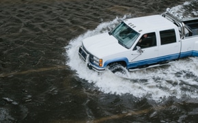 A truck wrecklessly driving through a flood area